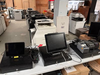 de nombreux ordinateurs portables et écrans posés sur une table dans un entrepôt