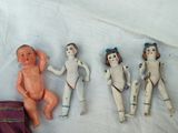 five small dolls sitting next to each other on a white sheet