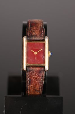 an image of a wrist watch with a red face on a black stand