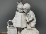 a white statue of two children with a basket and a lamp