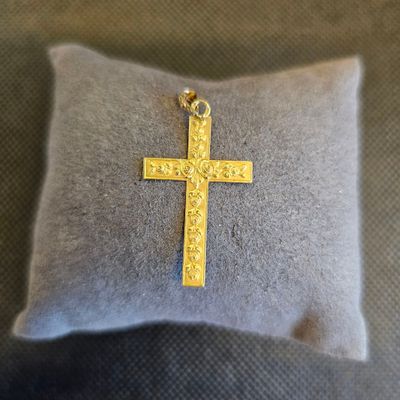 un gros plan d'une croix posée sur un oreiller, lui-même posé sur un autre oreiller