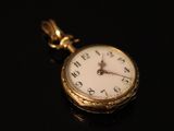 an antique pocket watch on a black surface with a black background