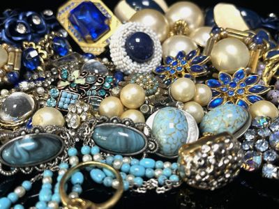 un tas de bijoux posés sur une table, sur fond noir