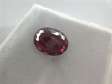 a close up of a red ruby stone on a white surface