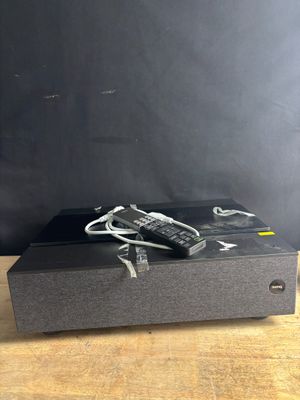 une boîte noire munie d'une télécommande, posée sur une table en bois