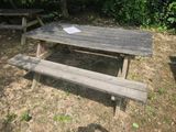 une table de pique-nique sur laquelle est posé un livre, au milieu d'un champ
