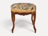 un petit tabouret en bois avec une assise rembourrée à motifs floraux