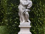 a statue of a boy holding a tennis racket in a garden