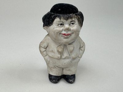 une petite figurine en céramique représentant un garçon coiffé d'un chapeau