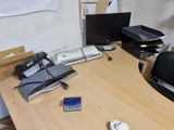 a desk with a laptop, phone, printer, and other items on it