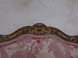 a pink and gold couch with a red dot on it