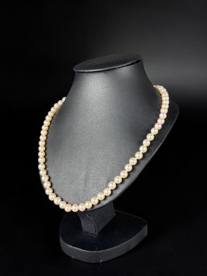 a pearl necklace on a mannequin stand against a black background