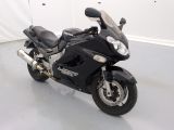 une moto noire garée dans une pièce aux murs blancs