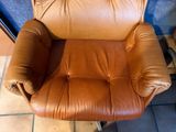 a brown leather chair that is sitting on a tile floor