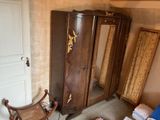 a wooden armoire with a mirror and a chair in the corner