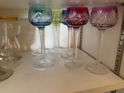 Plusieurs verres à vin sont alignés sur une étagère dans une cuisine.
