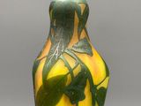 un vase jaune orné de feuilles vertes, posé sur une table