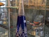 une vitrine en verre sur laquelle est posé un vase bleu