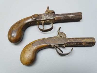 une paire de pistolets anciens en bois posés sur une surface blanche