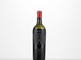 une bouteille de vin posée sur une table à côté d'un mur blanc