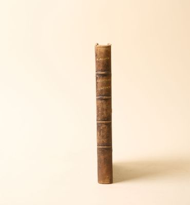 un vieux livre posé sur une table à côté d'un mur blanc