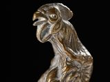 a bronze statue of a bird on a black background