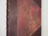 an old book with a brown cover sitting on top of a white table