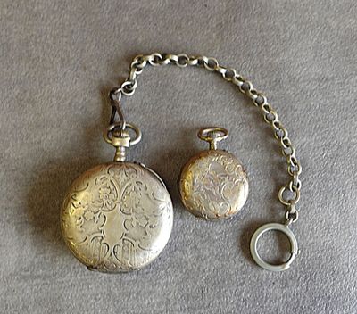 une montre de poche en argent et un porte-clés posés sur une table