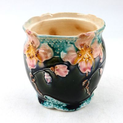 un petit vase sur lequel sont peintes des fleurs sur un fond blanc