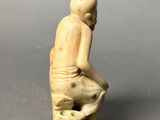 statue of a man sitting on a rock with his foot on the ground
