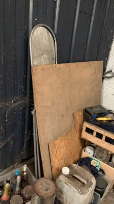 un tas de bric-à-brac dans un garage, à côté d'une porte métallique