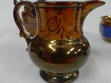 a gold pitcher sitting on a table next to a small jar