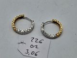 two gold and silver hoop earrings on a white surface