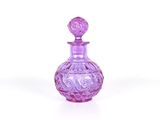 flacon de parfum en verre violet orné d'un motif décoratif sur le bouchon