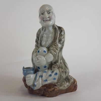 une figurine représentant un homme assis sur un rocher avec un oiseau