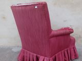 a pink chair with ruffles on it in front of a wall