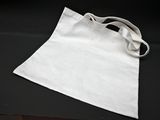 a white bag on a black table with a pair of scissors