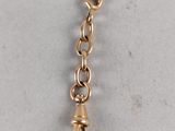 a close up of a gold chain with a small tear hanging from it