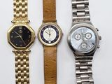 three watches are sitting on a white surface next to each other