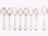 six silver spoons are lined up in a row on a white surface