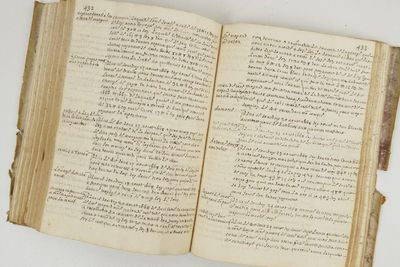 un vieux livre ouvert, sur lequel on peut lire des mots, posé sur une table