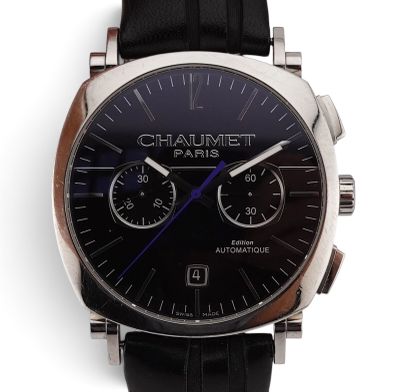 La montre est dotée d'un cadran noir et d'un bracelet en cuir noir.