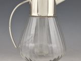 a glass pitcher with a silver lid on a table