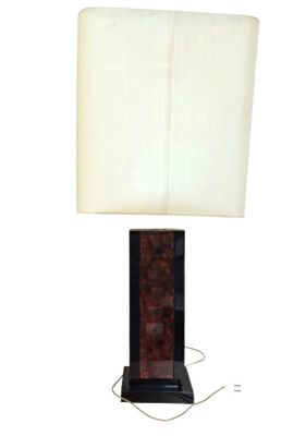 La lampe de table est en bois et est équipée d'un abat-jour blanc.