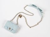 un gros plan sur un petit sac à main bleu orné d'un nœud et suspendu à une chaîne