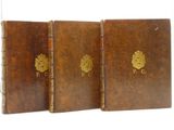 three brown leather books with gold emblems are stacked on top of each other