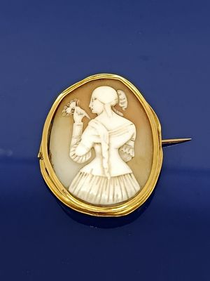 une image représentant une femme tenant un oiseau dans la main, sertie dans une broche en or