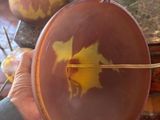 a person holding a brown bowl with a yellow leaf on it