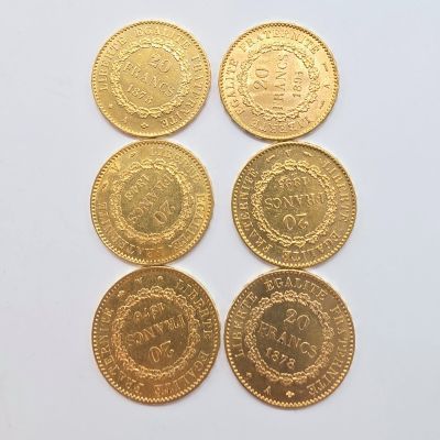 six pièces d'or présentant des motifs différents, posées sur un fond blanc
