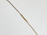 a gold bracelet with a long chain on a white background